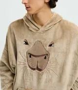 Buzo tipo manta de corte oversize confeccionado en tejido fleece de tacto suave y aspecto peludo. Presenta capucha, mangas largas con puños ajustados y un amplio bolsillo frontal tipo canguro. Incluye un diseño bordado en relieve de una capivara en el frente.