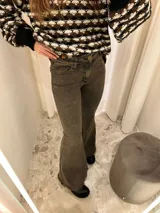 Jean de corte acampanado con cintura alta, confeccionado en denim azul oscuro. Presenta costuras en contraste y un acabado deshilachado en el ruedo.