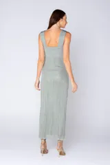 Vestido largo de tejido acanalado con sutil brillo metalizado, color verde menta. Presenta un escote cruzado con un nudo central en el busto y tirantes anchos, con una silueta ajustada en el torso y caída recta.