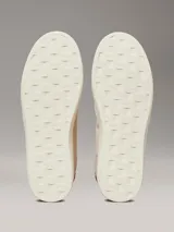 Zapatillas urbanas Calvin Klein Jeans color crema, con logo "CK" bordado en el lateral y detalle en color borgoña en el talón. Confeccionadas en lona y gamuza.