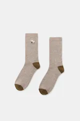 Calcetines de media caña en color beige melange con puntera y talón en contraste color marrón. Presentan un pequeño bordado de flores en la parte superior.