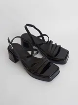 Sandalias negras de charol con plataforma, taco cuadrado y tiras finas.