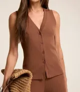 Blusa estilo chaleco, confeccionada en ribana negra, con abotonado delantero, sin mangas y con textura acanalada.