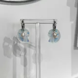 Aros colgantes con argolla de acero quirúrgico hipoalergénico y dije de acrílico con forma de caracol y perla de río natural.