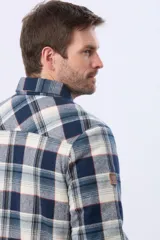 Campera leñadora de viyela a cuadros en tonos beige y azul oscuro, con interior forrado en corderito, cierre frontal con botones y dos bolsillos con solapa en el pecho.