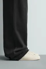 Zapatilla de cordones con diseño minimalista, parte superior lisa y suela con volumen. Presenta un detalle de pieza a contraste en la parte posterior.