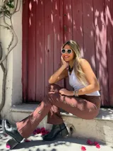 Pantalón marrón acampanado de gabardina elastizada con ojalillos metálicos en los laterales.