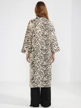 Camisa larga de lino 100% italiano, con estampado animal print que combina motivos de cebra y leopardo. Presenta un corte de estilo japonés, escote en V con tres botones delanteros y mangas tres cuartos anchas.