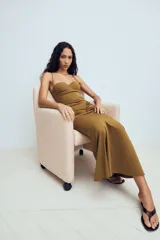 Vestido largo color tostado con diseño estilo corsé, escote corazón con aros y tirantes finos. Presenta un corte ajustado en la cintura con detalle de frunces laterales que aportan volumen a la falda.