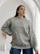 Sweater gris de tejido de punto con cuello redondo y mangas largas. Presenta un diseño con rombos y flecos.