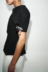 Top rosado con estampado de lunares fucsia, de cuello redondo y mangas cortas abullonadas con pliegues. Cuenta con escote en V en la espalda y cierre con cremallera oculta.