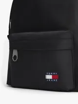 Mochila negra de estilo deportivo con diseño curvo, compartimento principal con cierre y bolsillo exterior con cremallera. Presenta el logo de Tommy Jeans en el bolsillo delantero y correas acolchadas y ajustables.