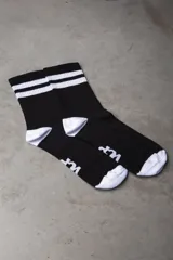 Medias deportivas de caña media, color negro con dos rayas blancas horizontales en el puño superior. Presentan puntera y talón en color blanco, con un detalle de logo estampado en el empeine.