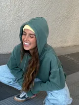 Buzo canguro verde con capucha y cordones ajustables.