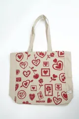Bolso tipo tote bag de color crudo con estampado de flores celestes y centros azul oscuro. Cuenta con doble asa de hombro en tono crudo y etiqueta con la marca en el frente.