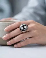 Anillo de acero de diseño redondo, con esmalte negro y detalles en nácar.
