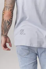 Remera blanca de manga corta con cuello redondo y un pequeño estampado azul en el pecho.