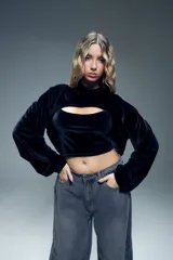 Canguro corto negro de terciopelo con capucha, mangas largas abullonadas con puños elastizados y abertura en el pecho.