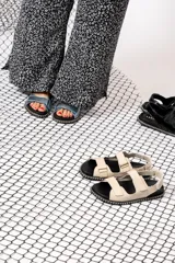 Sandalias chatas con base negra y tiras anchas de cuero sintético color celeste metalizado.