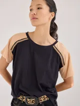 Remera de algodón con diseño bicolor, cuerpo en color negro y mangas en color beige. Presenta un detalle de galón trenzado en las costuras de las mangas raglán.