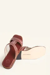 Sandalia plana de cuero color marrón, con tiras anchas y costuras blancas a la vista. Tiene punta cuadrada y un pequeño taco de 2 cm.
