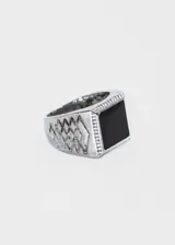 Anillo plateado de aleación de metales con piedra negra cuadrada en el centro.