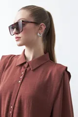 Camisa negra de estilo sastrero con cuello clásico, frente abotonado y mangas largas con puños ajustados. Presenta un diseño con hombreras sutiles que aportan estructura a la prenda.