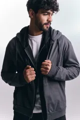 Campera deportiva de color gris oscuro con cierre frontal completo, capucha con cordones ajustables y puños acanalados.