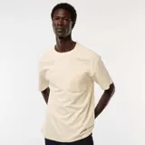 Camiseta de manga corta color crema, con cuello redondo y un bolsillo de parche en el lado izquierdo del pecho.