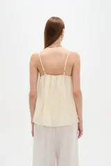 Musculosa de poliéster color marfil, con tirantes finos regulables, cuello cuadrado y diseño holgado, decorada con bordados de estrellas.