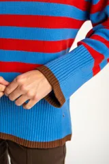 Sweater de punto con diseño de rayas horizontales en azul y rojo, cuello redondo y puños con terminación en color marrón.