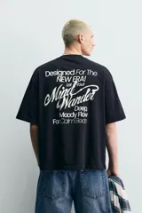 Remera de corte holgado confeccionada en algodón con interior de tejido rizo. Presenta cuello redondo, manga corta y estampados con texto en contraste en la parte frontal.
