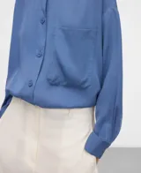 Camisa de lyocell color azul con cuello mao, botonadura frontal, manga larga con puño abotonado y un bolsillo en el pecho.