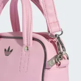Bolso pequeño Adidas Adicolor XS de diseño estructurado en color rosado. Cuenta con doble asa superior, correa ajustable y desmontable para el hombro, cierre de cremallera y logo del trébol bordado en el frente.