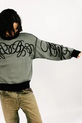 Sweater reversible de tejido de punto con diseño gráfico estilo tribal. Un lado presenta base negra con detalles en gris, mientras que el otro lado presenta base gris con detalles en negro. Posee cuello redondo, mangas largas y puños acanalados.