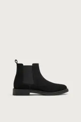 Bota chelsea de hombre en piel con acabado serraje de color negro, paneles elásticos laterales, puntera redonda y suela con ligero tacón.