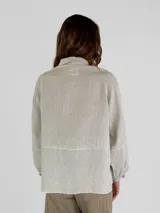 Chaqueta color amarillo de lino, con cuello camisero, cierre frontal con botones, mangas largas con puños abotonados y dos bolsillos de parche en el pecho.