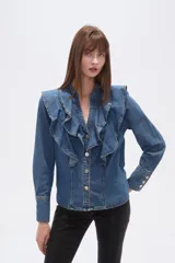 Camisa de jean azul con volados grandes en el frente, escote en V y cierre frontal con botones plateados.