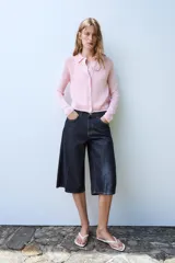 Chaqueta de punto color rosado con cuello polo, manga larga y cierre frontal con botones.