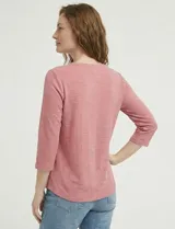 Blusa de manga tres cuartos color rosado, confeccionada en modal texturizado. Presenta un escote en V con cuello a la base y apliques nacarados en el área del escote.