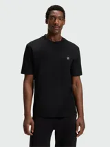 Remera de corte regular, color negro, con cuello redondo y detalle de monograma metálico en el pecho.