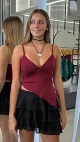 Top color bordó con escote en V, tirantes finos y bajo asimétrico.