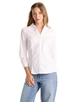 Camisa blanca de algodón con cuello camisero y escote en V. Presenta detalles plisados en el frente, cierre central con botones y mangas tres cuartos con puños abotonados. Los laterales están confeccionados en tejido modal para mayor comodidad.
