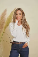 Buzo tejido de punto color blanco, con escote en V, mangas largas con detalle de botones en los puños y aberturas laterales en el ruedo.