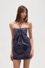 Top strapless de viscosa con estampado de azulejos en tonos azul y blanco. Presenta un diseño con cuello halter, detalle de fruncido central y un lazo decorativo en el frente.