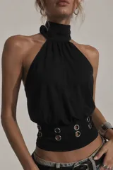 Top halter negro con cuello alto y silueta fluida, con detalle de ojales metálicos en la cintura.