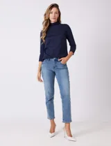 Jean azul de calce semi-ajustado, estilo Mom Slim, de tiro alto, relajado en la cadera y muslos, con pierna que se angosta levemente hacia el tobillo. Tiene pretina clásica con pasadores para cinturón, cierre frontal con cremallera y botón metálico, y bolsillos delanteros y traseros.