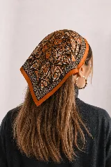 Pañuelo cuadrado con estampado geométrico y de cadenas en tonos naranja, negro y blanco, con bordes anchos naranjas.