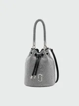 Cartera tipo balde mini de Marc Jacobs, con cuerpo cubierto de strass plateados, asa corta trenzada y correa larga de cuero negra. Cierre superior con cordón ajustable y logo de la marca en el frente.