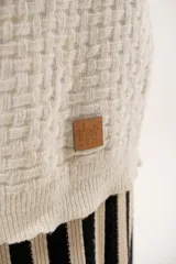 Buzo oversize color beige confeccionado en tejido sintético con destellos de lurex, cuello redondo y manga larga.